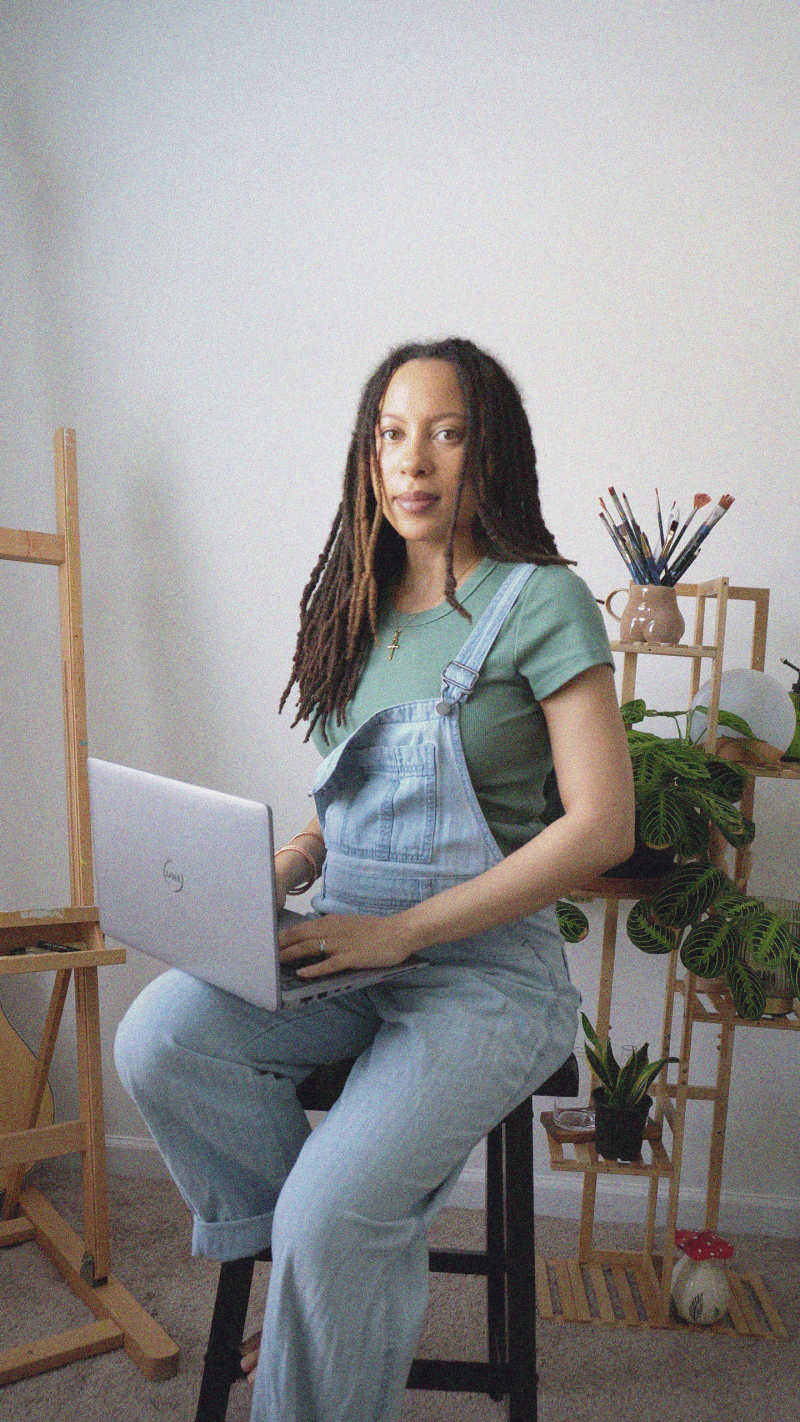 Elle Knight holding laptop and fixing her hair.